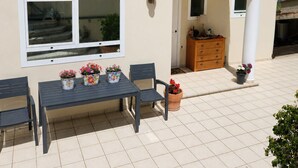 A house with a tiled roof, a patio with a table and chairs, and a small wooden cabinet. - Private villa with infinity pool, Hot Spring hot tub and views in Mijas (Mijas)