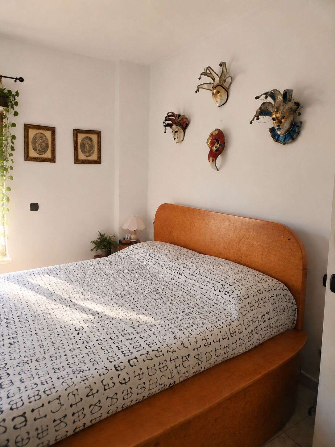 Un dormitorio con una cama de madera, un edredón estampado y máscaras decorativas en la pared.