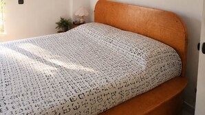 A bedroom with a wooden bed, a patterned bedspread, and decorative masks on the wall. - Private villa with infinity pool, Hot Spring hot tub and views in Mijas (Mijas)