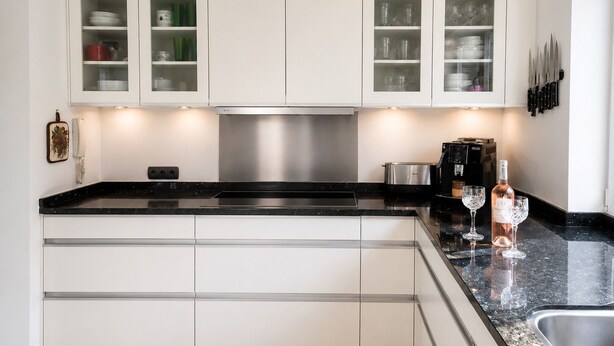 A modern kitchen with white cabinetry, a black countertop, and a stainless steel range hood. - Private villa with infinity pool, Hot Spring hot tub and views in Mijas (Mijas)