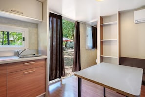 Una kitchenette compacta con ventana, un lavamanos y armarios de madera.