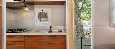 Une cuisine de taille réduite, avec des meubles de rangement en bois, une cuisinière à gaz et un évier.