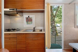 Een kleine keuken met houten kastjes, een gasfornuis en een spoelbak.