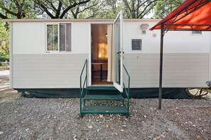 A small, single-story mobile home with a door open to a room, a small window, and a number '33' on the side. - Mobile home with air conditioning and 3 shared pools (Bucine)