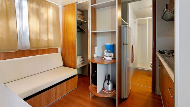 Een knus ingerichte kamer met een slaapbank, een koffiezetapparaat en een kleine tafel.