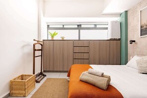 Ein Schlafzimmer mit einem Bett, einem Holzschrank, einem Korbwäschekorb und einem Fenster mit Blick.