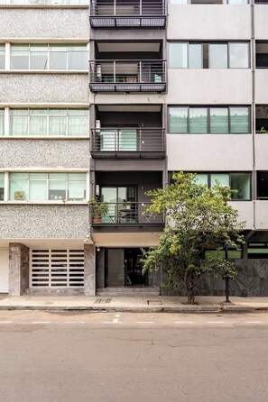A multi-story building with balconies, a tree in front, and a garage entrance. - The Modern Loft Reforma (Mexico City)