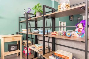 Ein Zimmer mit Bücherregal, Schreibtisch und einem Spielpferd.