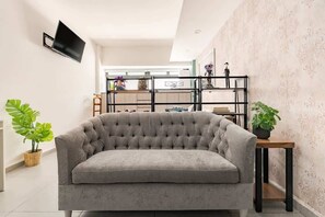 A living room with a grey sofa, a mounted TV, and a shelving unit with decorative items. - The Modern Loft Reforma (Mexico City)