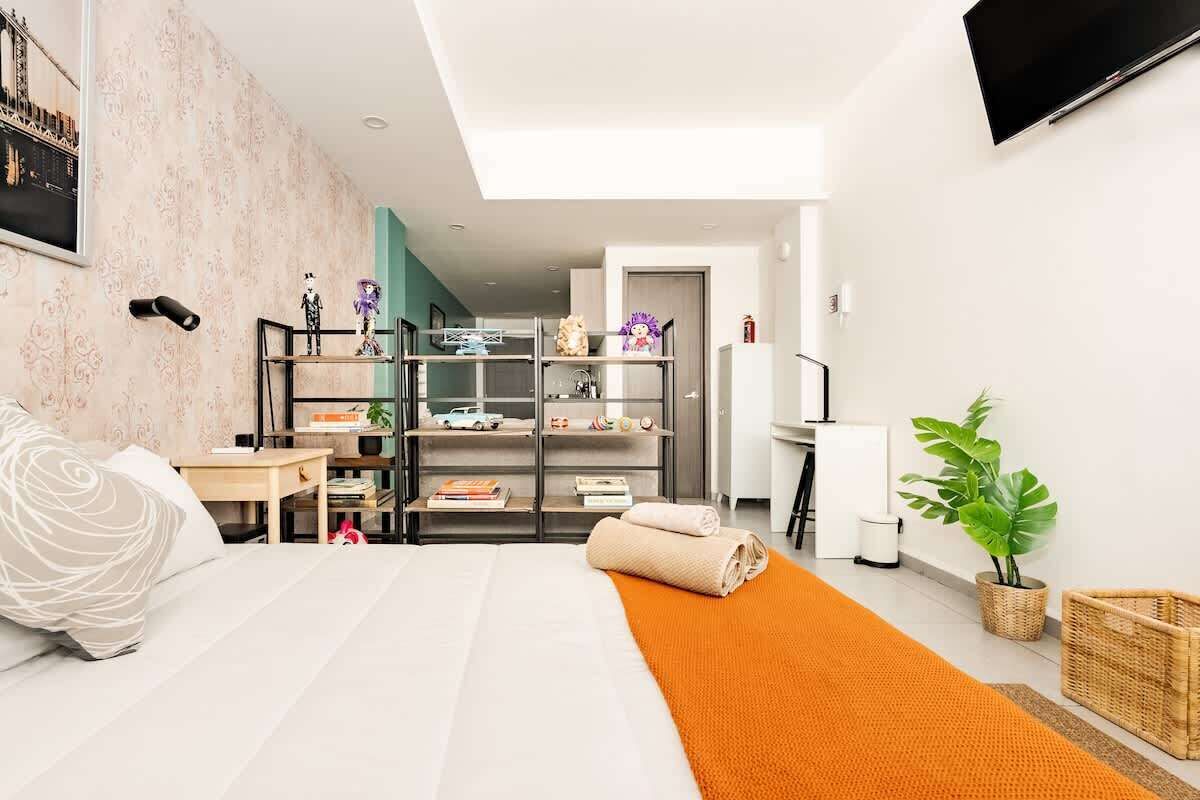 Une chambre à coucher moderne, équipée d’un lit, d’un bureau, d’une bibliothèque et d’un téléviseur.