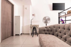 A room with a sofa, a desk with a stool, a wardrobe, a fan, and a television on the wall. - The Modern Loft Reforma (Mexico City)