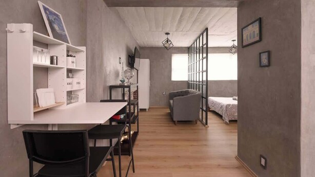 Ein modernes Interieur mit Essbereich, einer Couch und einem Bett im Hintergrund.