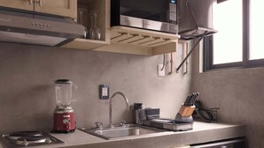 Eine kompakte Küche mit Einbau-Mikrowelle, Spüle, Mixer und Waschmaschine.