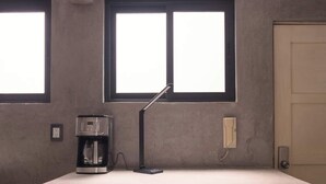 Eine kompakte Küchenzeile mit integriertem Kühlschrank, einer Kaffeemaschine und einem kleinen Spülbecken.