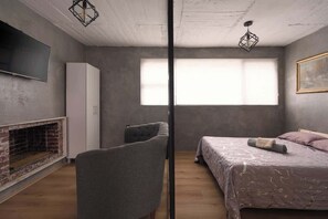A bedroom with a bed, a chair, a TV, a wardrobe, and a fireplace. - Nice & Cozy loft near to Reforma (Mexico City)