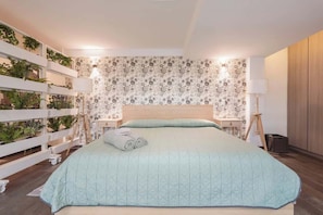 A bedroom with a bed, a white wall with a floral pattern, a wooden headboard, a nightstand, a lamp, and a plant wall. - The Nice & Cozy Urban Green Haven (Ciudad de México)