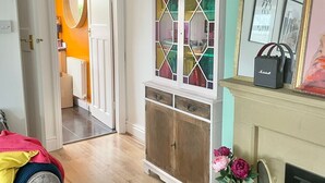 Une pièce avec un plancher en bois, une armoire blanche aux portes en verre, une cheminée et un miroir au mur.