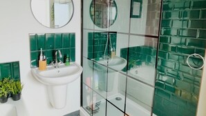 Une salle de bain moderne avec une douche à parois de verre, un lavabo blanc et des murs recouverts de carreaux verts.