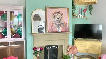 A living room with a fireplace, a television, and a variety of decorative items.