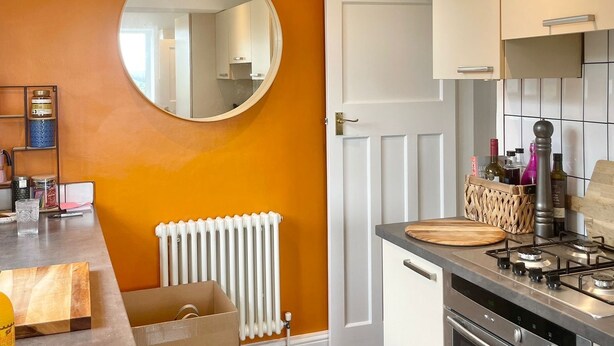 Une cuisine moderne avec un îlot central, des meubles blancs et un grand miroir au mur.
