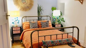 Une chambre à coucher avec un lit, une lampe suspendue, un miroir et une commode en bois.