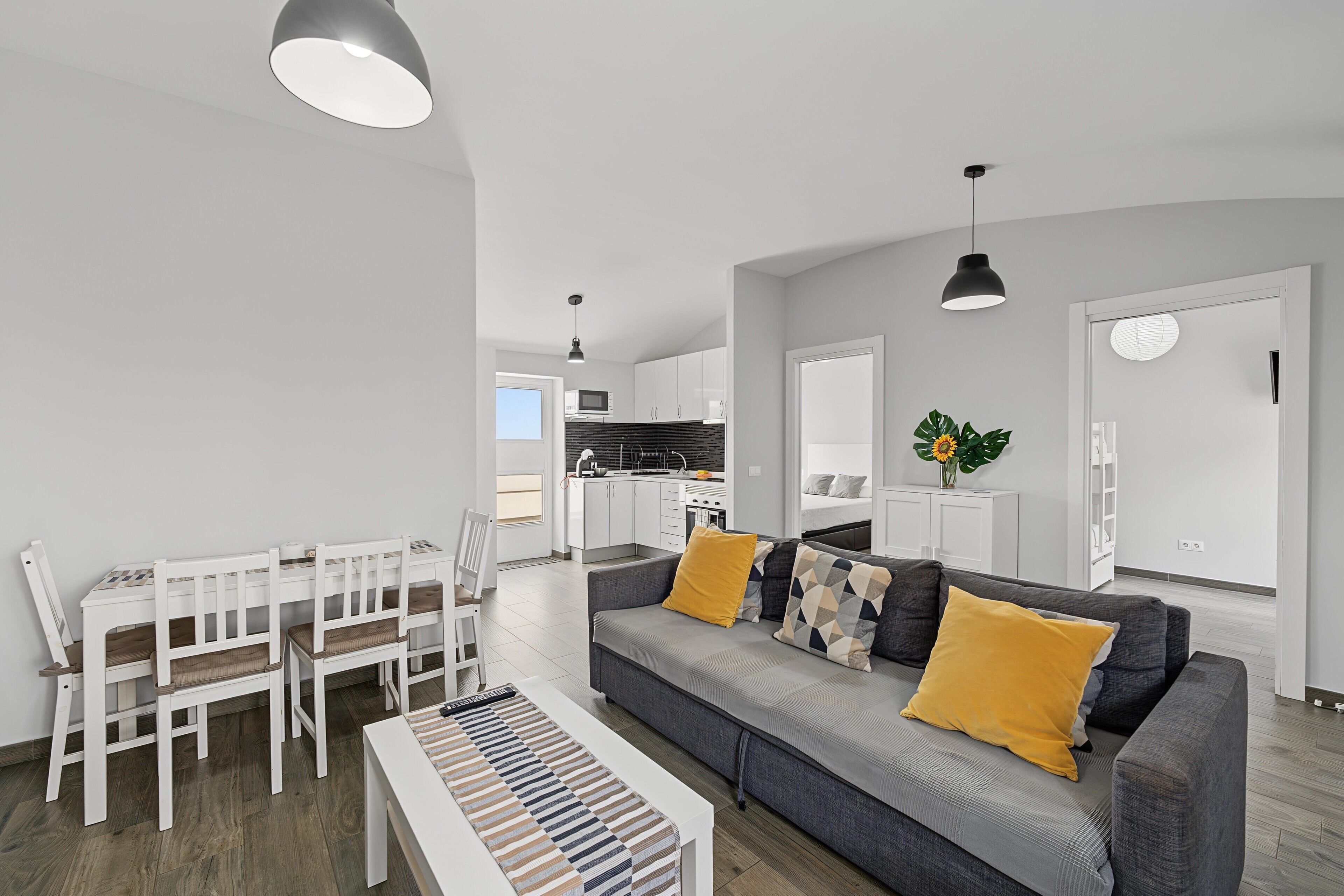Een moderne woonkamer met een grijze bank, een witte salontafel en een gestreept tapijt.