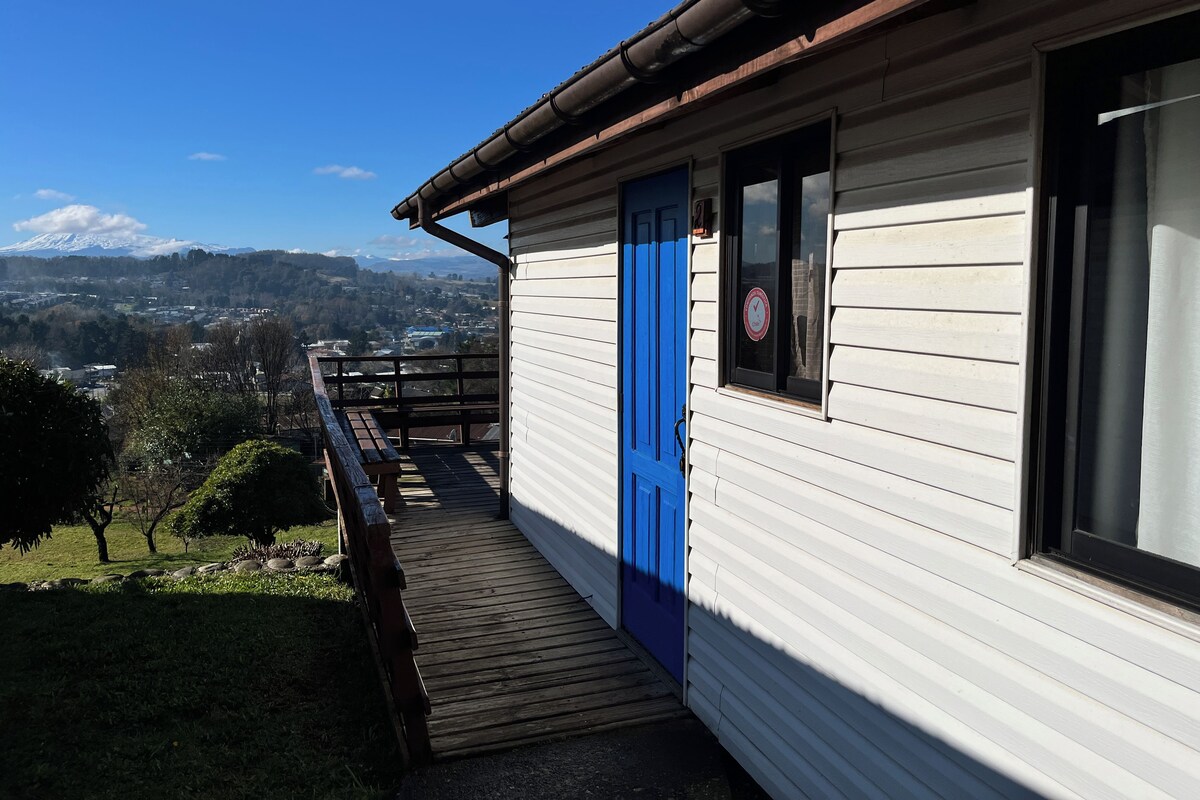 A building with a blue door, a wooden deck, and a view of a mountain range.