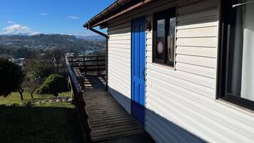 En byggnad med en blå dörr, ett trädäck och utsikt över ett bergskedja.