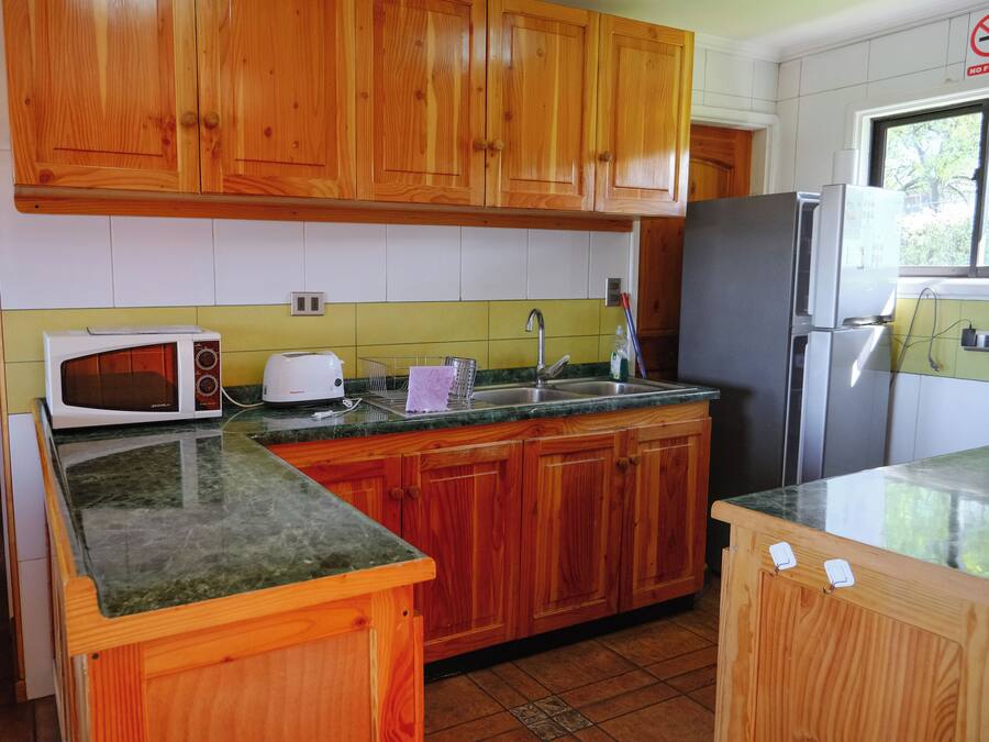 A kitchen with wooden cabinets, a microwave, a toaster, a sink, and a refrigerator.