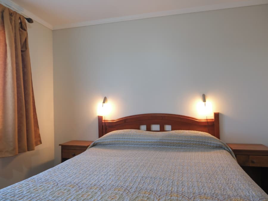 A bedroom with a bed, two bedside tables, and a nightstand.