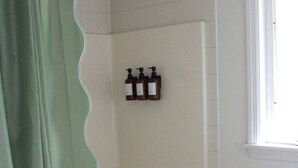 A bathroom with a shower, a sink, and three bottles of shampoo on the wall.