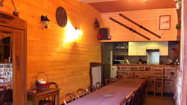 Un espace repas avec une longue table, des chaises et une cuisine en arrière-plan.