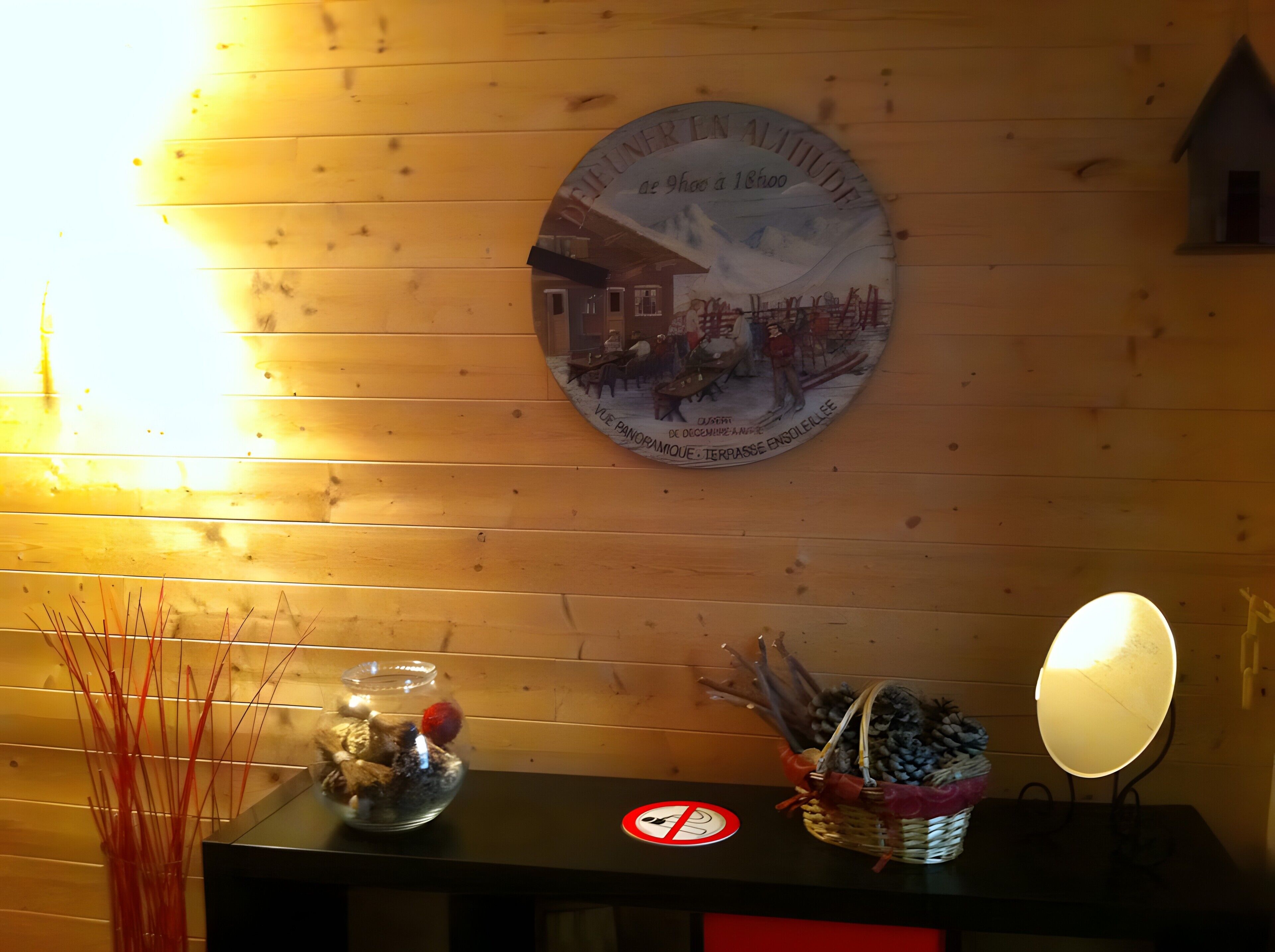 A wooden wall with a circular plaque, a table with a no-smoking sign, and a decorative basket.