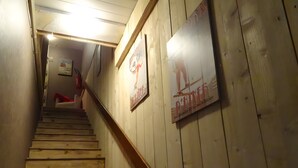 Un escalier en bois, doté d’une rampe, mène à une pièce dont le mur est orné d’une affiche.