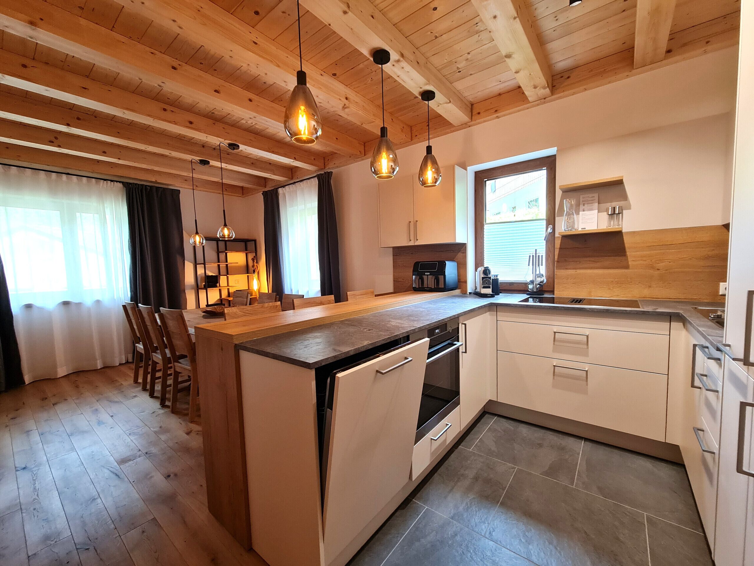 Een moderne keuken met houten balken, een centraal eiland en hanglampen.