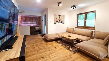 Een moderne woonkamer met een hoekbank, een salontafel en een flatscreen televisie.