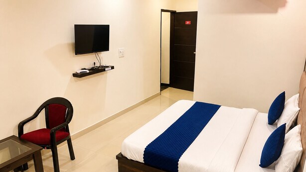 Ein Hotelzimmer mit Bett, Schreibtisch, Sessel, Fernseher und Kleiderschrank.