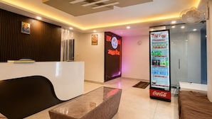 Eine Hotelhalle mit einer Rezeption, einer Sitzecke und einem Coca-Cola-Kühlschrank.