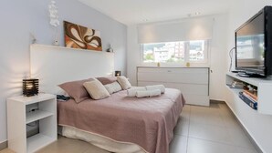 A modern bedroom with a bed, bedside tables, a TV, and a window with a view. - Australis Apartamento Micro-centro (Ushuaia)