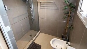 A bathroom with a glass-enclosed shower, a toilet, and a sink. - Australis Apartamento Micro-centro (Ushuaia)