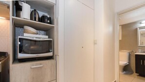 A compact kitchen with a microwave, a coffee maker, and a kettle on the countertop. - Australis Apartamento Micro-centro (Ushuaia)