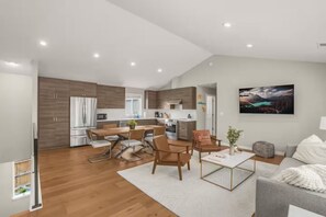 Eine moderne Küche mit Einbaugeräten, ein Essbereich mit Holzmöbeln und ein Wohnzimmer mit Sofa und Couchtisch.