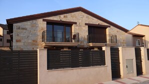 A two-story house with a stone facade, a gated entrance, and a small balcony. - Country Villa Puerta del Gallo (Molina de Aragón–Alto Tajo) (Molina de Aragón)