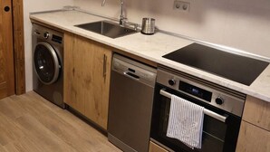 A compact kitchen with wooden cabinets, a built-in microwave, a dishwasher, and an oven. - Country Villa Puerta del Gallo (Molina de Aragón–Alto Tajo) (Molina de Aragón)