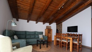A living room with a sofa, a coffee table, a TV, and a dining area with chairs and a table. - Country Villa Puerta del Gallo (Molina de Aragón–Alto Tajo) (Molina de Aragón)