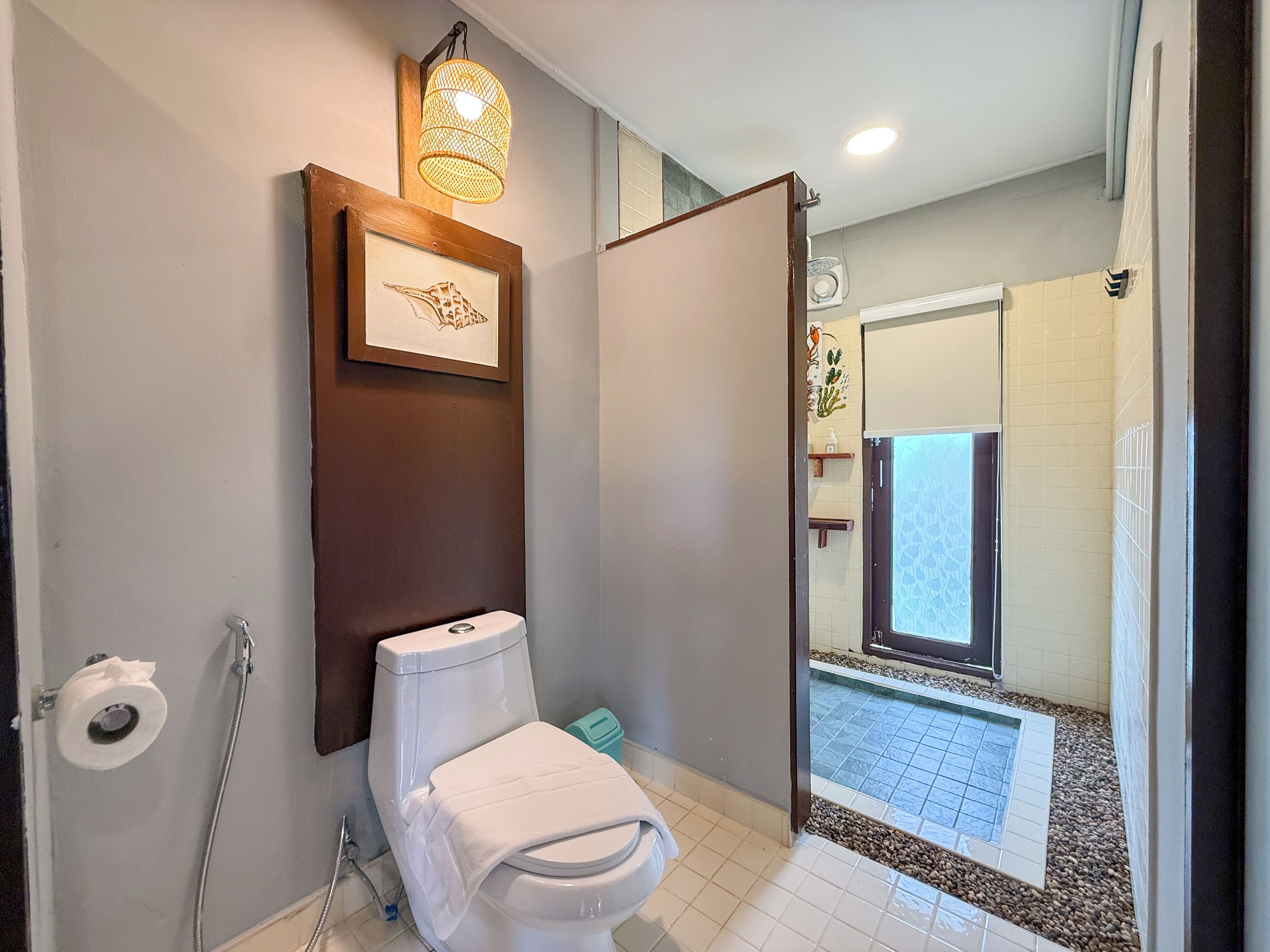 Un baño con inodoro, ducha e imagen enmarcada en la pared.