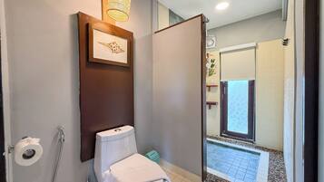 Un baño con inodoro, ducha e imagen enmarcada en la pared.