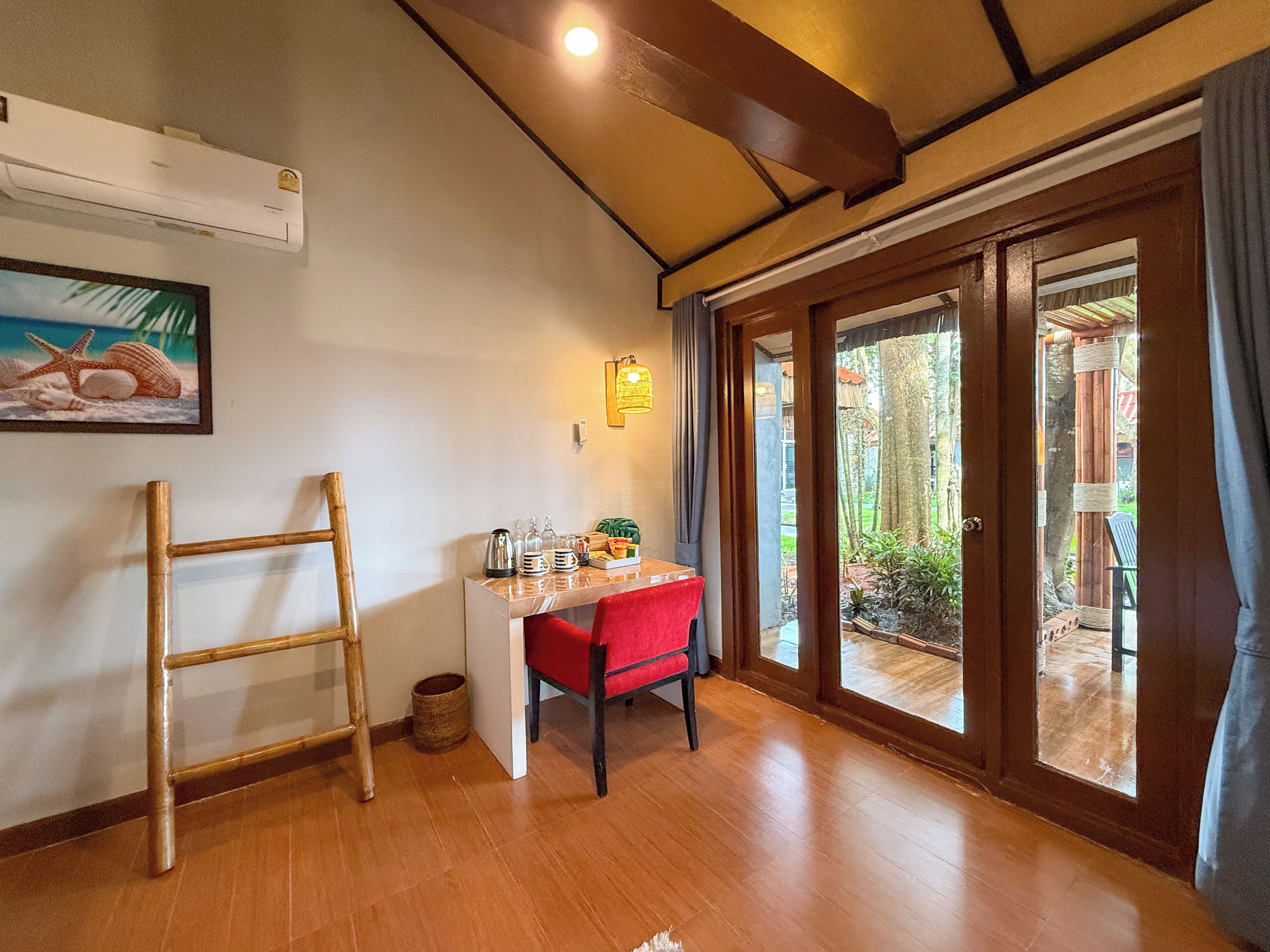 A room with a wooden desk, a red chair, a small basket, and a framed picture on the wall.