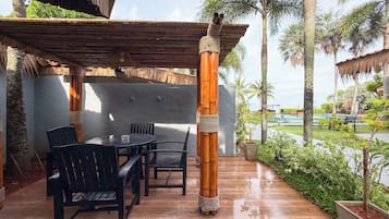 Un patio al aire libre con una mesa y sillas de madera, rodeado de macetas con plantas y palmeras.