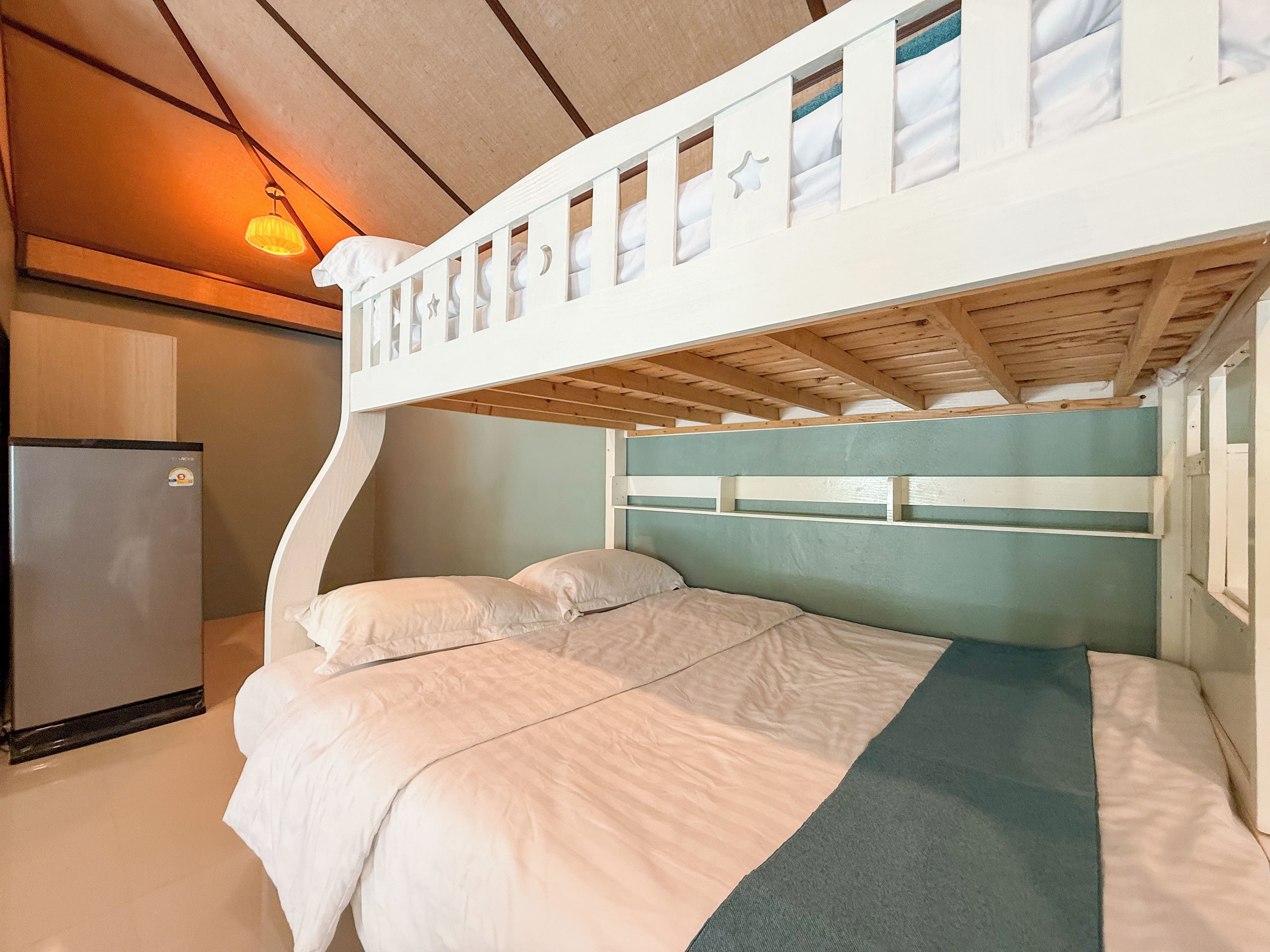 A bunk bed with a wooden headboard, a bedside table, and a refrigerator.